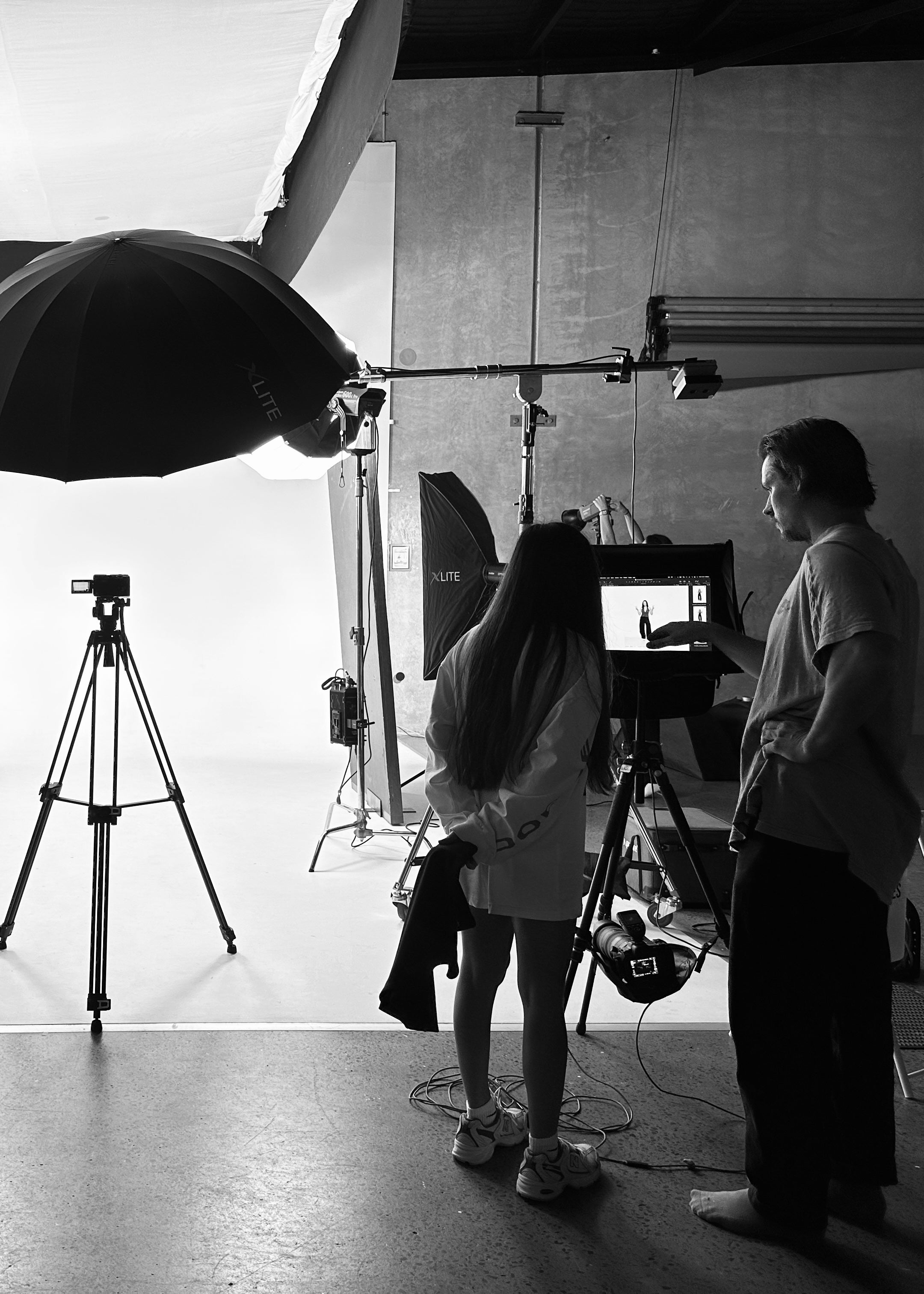 Black and white behind-the-scenes of a Formation shoot with photographer and crew on set preparation