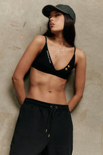 Model wearing Formation Xali Bralette in noir, featuring Formation embroidery logo and gold-toned buttons.