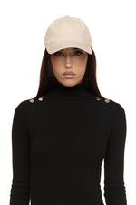 Close up of model wearing Formation Xaria bodysuit in noir with gold-toned buttons