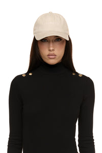 Close up of model wearing Formation Xaria bodysuit in noir with gold-toned buttons