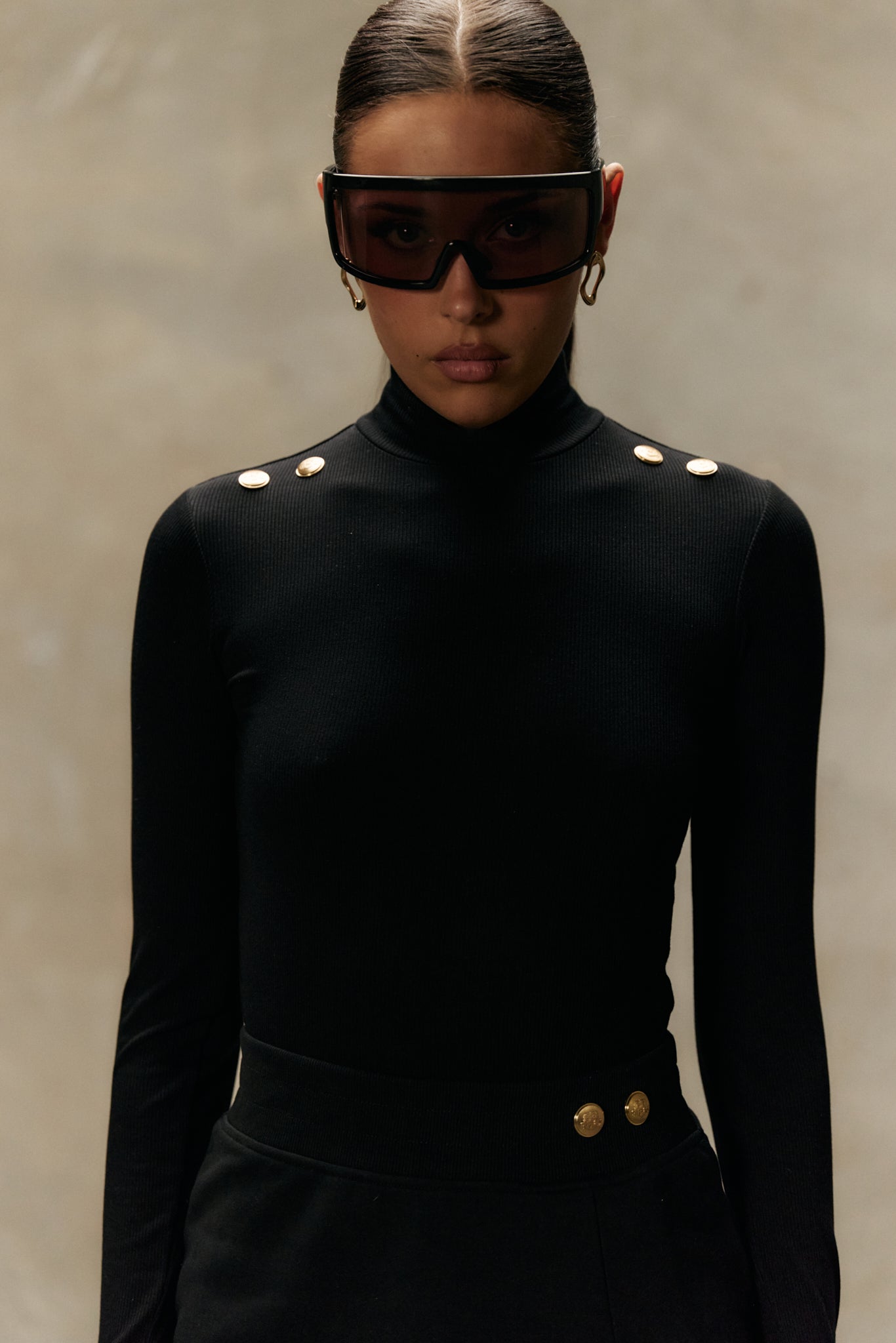 Model wearing formation noir xaria bodysuit and xya skirt, with gold-toned signature accents