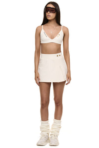 Model wearing Formation Xali bralette in ivory with embroidery logo and gold-toned buttons