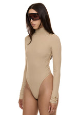 Semi side view of model wearing Formation Xaria bodysuit in desert with gold-toned buttons