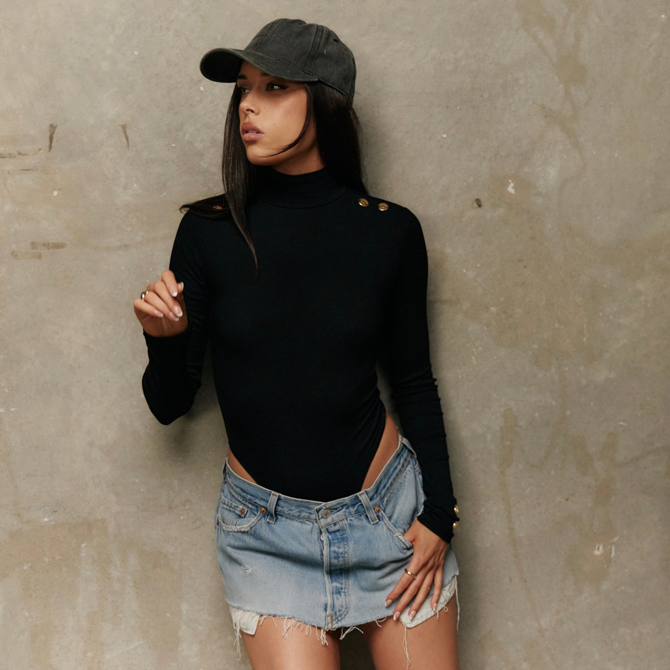 Model wearing Formation noir xaria bodysuit with gold toned buttons