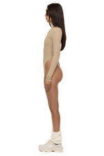 Model wearing Formation Xaria bodysuit in desert side view showing gold-toned buttons