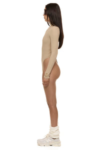 Model wearing Formation Xaria bodysuit in desert side view showing gold-toned buttons