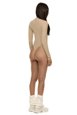 Back view of model wearing Formation Xaria bodysuit in desert side view showing gold-toned buttons