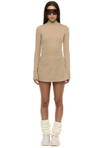 Model wearing Formation Xaria bodysuit in desert side view showing gold-toned buttons