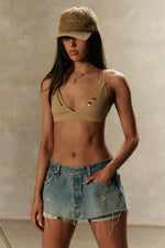 Model wearing Formation Xali Bralette in desert with embroidery logo and gold-toned buttons