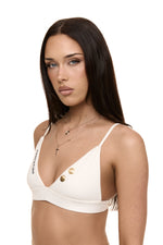 Model wearing Formation Xali Bralette in ivory with embroidery logo and gold-toned buttons