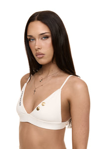 Model wearing Formation Xali Bralette in ivory with embroidery logo and gold-toned buttons