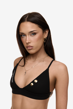 Model wearing Formation Xali Bralette in noir, featuring Formation embroidery logo and gold-toned buttons.