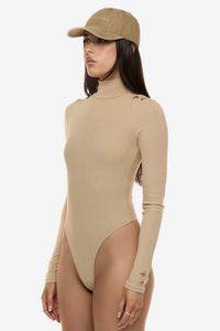 Semi side view of model wearing Formation Xaria bodysuit in desert with gold-toned buttons