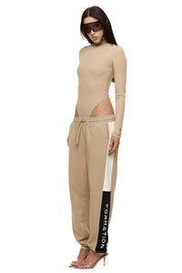 Model wearing Formation Xaria bodysuit in desert semi side view showing gold-toned buttons
