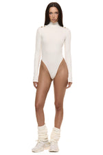 Model wearing Formation Xaria bodysuit in ivory with gold-toned buttons