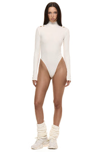 Model wearing Formation Xaria bodysuit in ivory with gold-toned buttons