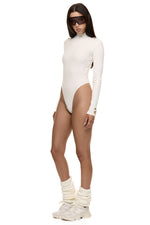 Semi side view of model wearing Formation Xaria bodysuit in ivory with gold-toned buttons