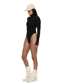 Semi side view of model wearing Formation Xaria bodysuit in noir with gold-toned buttons