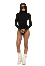 Model wearing Formation Xaria bodysuit in noir with gold-toned buttons