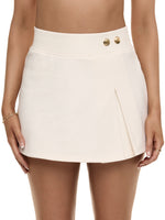 Close-up of model wearing Formation Xya Skirt in ivory with soft pleat accent and gold-toned buttons