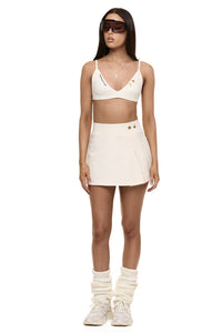 Model wearing Formation Xya Skirt in ivory with soft pleat and gold-toned buttons