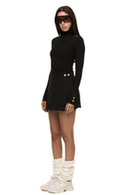 Model wearing Formation Xya Skirt in noir, semi side view with soft pleat and gold-toned buttons
